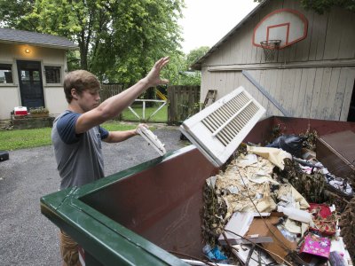 A man tossing junk into a dumpster